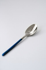 Silver or steel cutlery on an isolated background. Gilded teaspoon of blue color. Top view.
