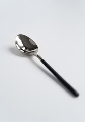 Silver or steel cutlery on an isolated background. Gilded teaspoon of black color. Top view.