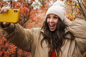 Brunette happy woman in knit hat taking selfie
