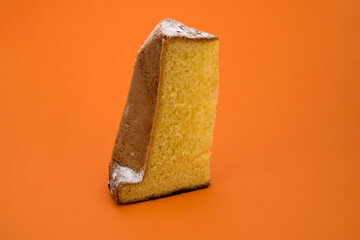 Pandoro, typical Italian Christmas dessert,  one slice with icing sugar isolated orange background