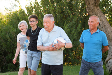 famiglia con nonni e nipote si diverte nel prato a giocare con il pallone