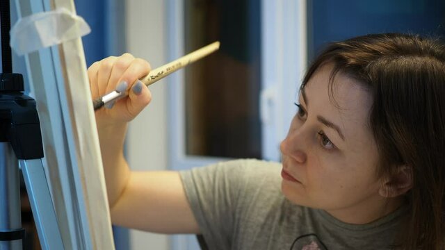 a young woman draws a picture with a brush in the Studio.