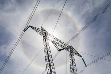 point de vue d'en bas d'une structure soutenant plusieurs fils électriques avec le soleil en...