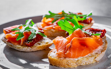 bruschetta with salmon,cherry tomatoes,fresh arugula and cream cheese on plate