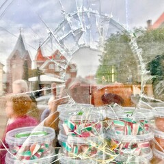 Zerbrochenes Schaufensterglas mit Süßigkeiten dahinter