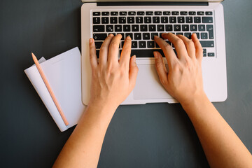 open notebook and laptop. person teenager young woman taking note in notebook. studying, learning. keyboard. online course. corona virus quarantine lockdown. online meeting, webinar. typing.