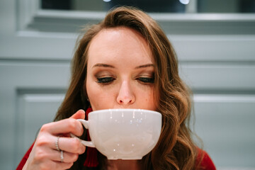 Beautiful woman tastes delicious coffee prepared by barista in a coffee shop.