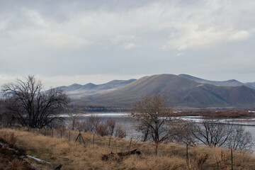 Fototapeta premium Beautiful winter landscape with snow-covered mountains, dry grass and a river in the foreground. Huntington, OR, USA