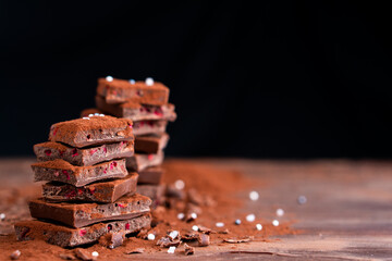 Organic food snack tasty sweet dessert milk dark chocolate bar macro closeup broken slide piece and fruit orange raspberry hazelnut nuts on cocoa cacao powder wooden table for new year Christmas gift