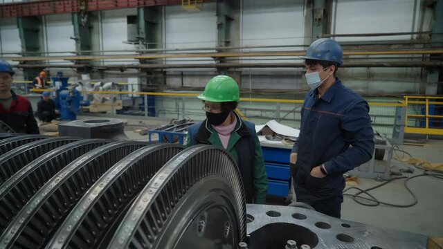 Turbine manufacturing plant. Modern production of a steam turbine. Quality control stand before final assembly. Workers wearing gloves and masks comply with the quarantine regime