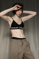 portrait of a young woman  in in trousers and a top. Model with hat and short hair. Natural clean face