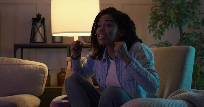 Excited african american woman celebrating win watching soccer match on tv