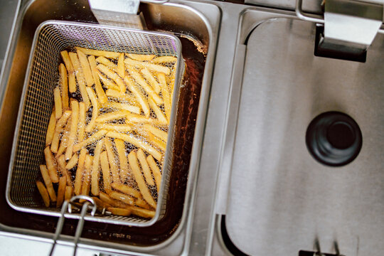 Top view of fries in deep fryer. Restaurant meal preparation, side dish