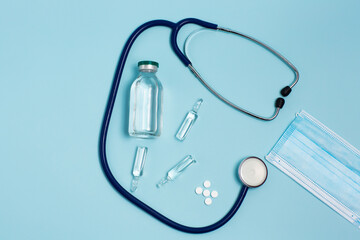 Composition of tablets, ampoules, mask and stethoscope on a blue background. Healthcare. Coronavirus, virus, flu or pneumonia. View from above. 