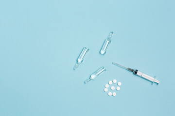 White pills, ampoules and syringe on a blue background. Banner with place for text. 