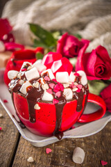 Hot chocolate or coffee latte cup for Valentine day morning. Crazy shake styled hot chocolate or latte with a lot of marshmallow and hearts sugar sprinkles, with gift boxes and roses flowers