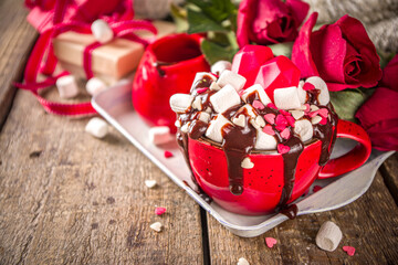Obraz na płótnie Canvas Hot chocolate or coffee latte cup for Valentine day morning. Crazy shake styled hot chocolate or latte with a lot of marshmallow and hearts sugar sprinkles, with gift boxes and roses flowers