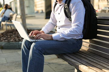 person sitting and typing on laptop outdoors close up