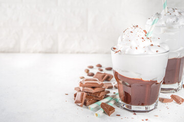 Hot chocolate milk shake, cold boozy cocktail with ice cream or whipped cream, with chocolate slices on white background copy space