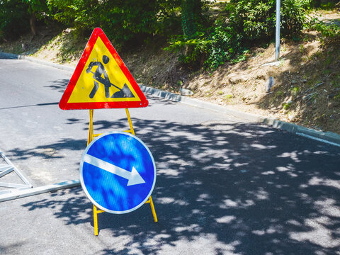 Round and triangular signs standing on the road symbolizing road construction