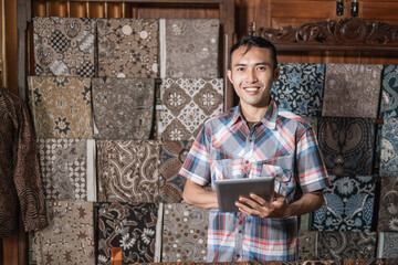 Naklejka na ściany i meble portrait of young customer service in traditional indonesian batik store