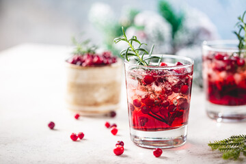 Refreshing drink with cranberries and rosemary on white background