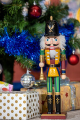 Nutcracker wooden toy standing in front of decorated Christmas tree in English House