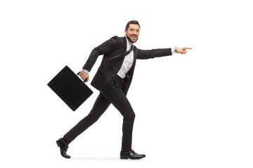 Handsome man in a black suit running with a briefcase and pointing forward
