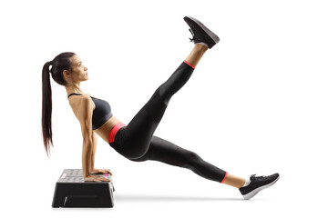 Young woman exercising on a step aerobic platform and lifting one leg up