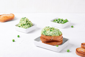 Pate with green peas on toasted bran bread served on the white table with the ingredients. Healthy vegan paste 