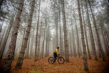 Naklejka premium Young man biking through autumn forest