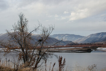 Beautiful winter landscape with snow-covered mountains, dry grass and a river in the foreground. Huntington, OR, USA