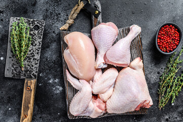 Raw chicken portions for cooking and barbecuing with skinless breasts, drumstick and wings. Black background. Top view