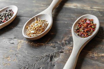 spices assorted peppers, dried onions and paprika flakes on wooden spoons
