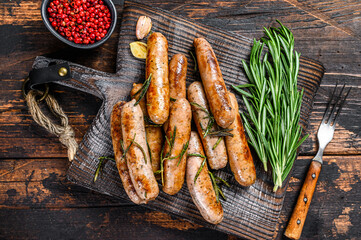 Grilling bavarian sausages on a cutting board. Dark wooden background. Top view