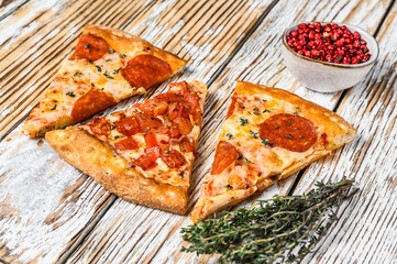 Pieces of pepperoni and tomato pizza. White wooden background. Top view