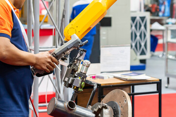 Fototapeta premium man or technician enter command information pass wireless remote for control automatic robot arm to do welding work in production