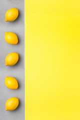 Yellow paper and gray concrete texture, fresh lemons on gray background, colors of year 2021, vertical, copy space