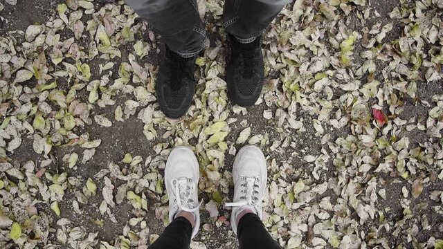 Firest person view of woman legs outdoors and man legs approach, couple dating during Saint Valentines day.