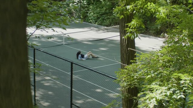 Girl on tennis court from far away