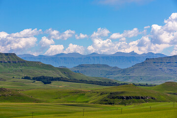 Fototapeta premium White clouds above blue mountains and green valley