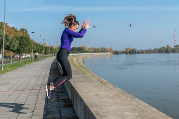 Young sexy sweaty muscular fit woman practicing outdoor jumping on the wall for hardcore cross...