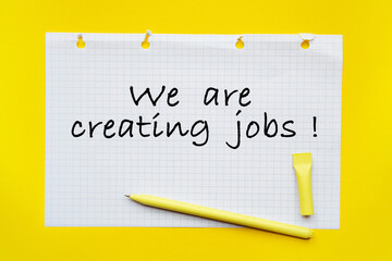 WE ARE CREATING JOB inscription on white list, yellow pen on a yellow background. a bright solution for business, financial, marketing concept