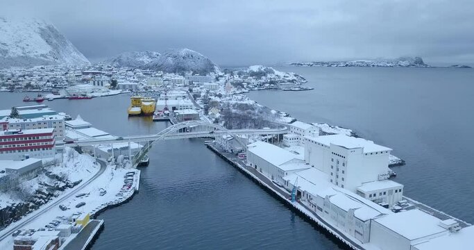 Breathtaking aerial drone footage. Flying over the industrial (fishery), seaside part of Alesund, the most beautiful town in Norway in winter time while everything is covered in a thick layer of snow.