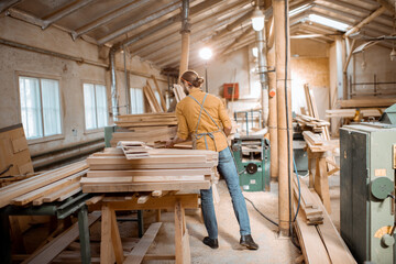 Naklejka na ściany i meble Carpenter carrying pine planks in the warehosue