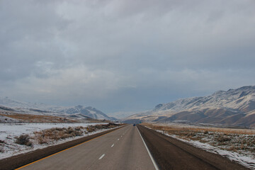 Highway in the middle of the mountains in a snowy winter. A beautiful asphalt road among the snow-covered mountains. Oregon, USA