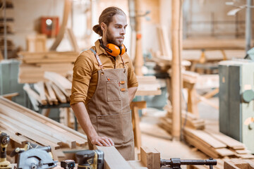 Portrait of a creative carpenter with headphones at the workshop