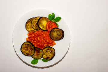 Fototapeta na wymiar Fried eggplant on a plate with bean garnish.. Top view, white background