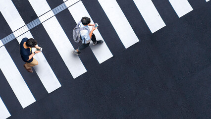 Human life in Social distance. Aerial top view with blur men and people with smartphone and group of people walking at pedestrian crosswalk on grey pavement street road with empty space.