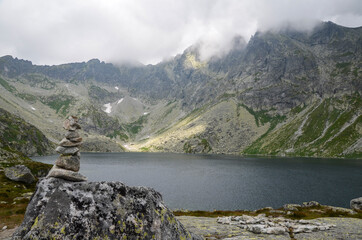 The largest mountain lake on slovakian side of High Tatras, Hincovo pleso in Mengusovska valley surrounded by rocky mountains under low clouds